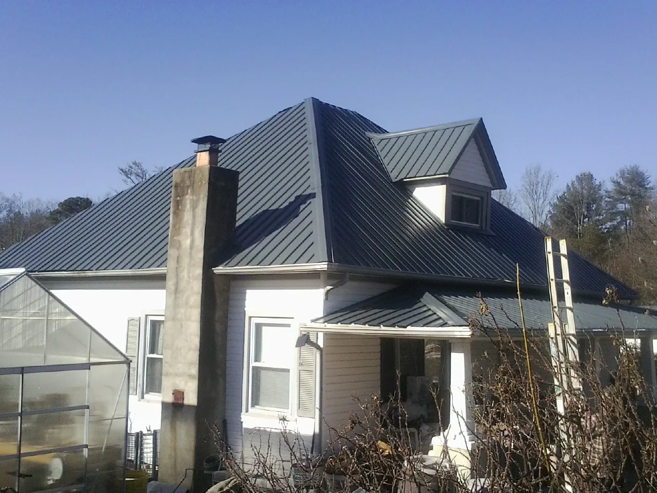 Dark blue standing seam metal roof on a white farmhouse with dormer — Slate & Tile Roof Repair by Roofing Brothers in Republic