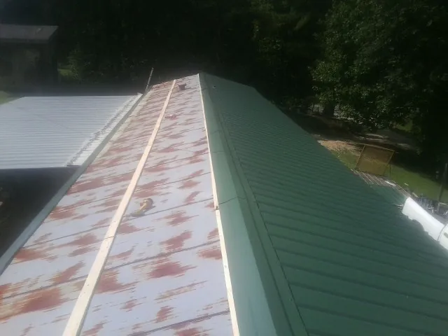 Old rusted panels beside newly installed green metal roofing — Wind Damage Roof Repair by Roofing Brothers in Republic